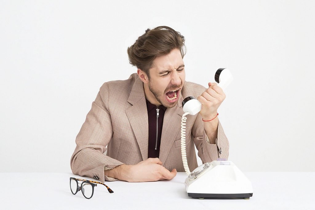 man wearing brown suit jacket mocking on white telephone 1587014 scaled 1 2048x1366